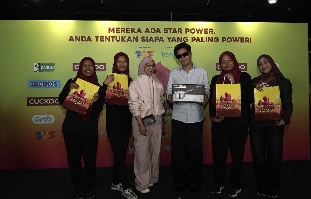 Haqiem Rusli memegang hadiah kotak peralatan dapur bersama ahli pasukannya memegang beg cenderahati di atas pentas AMT 2026
