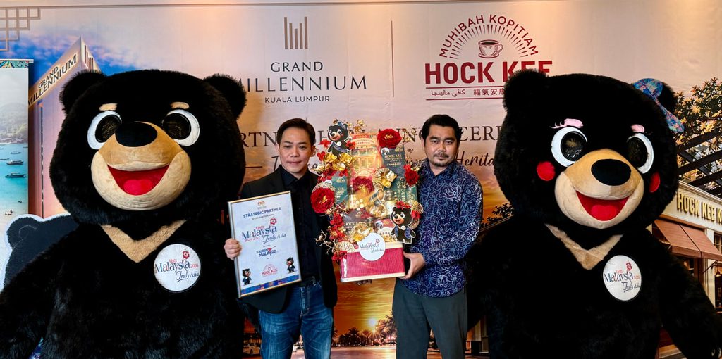 Wakil Hock Kee Kopitiam menerima sijil rakan strategik dan bakul cenderahati diapit dua maskot beruang kempen TMM