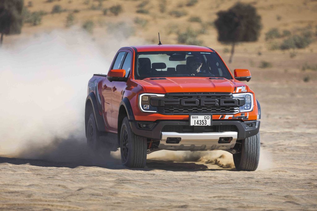 Kenderaan pacuan empat roda Ford Ranger Raptor berwarna oren dipandu laju di kawasan padang pasir