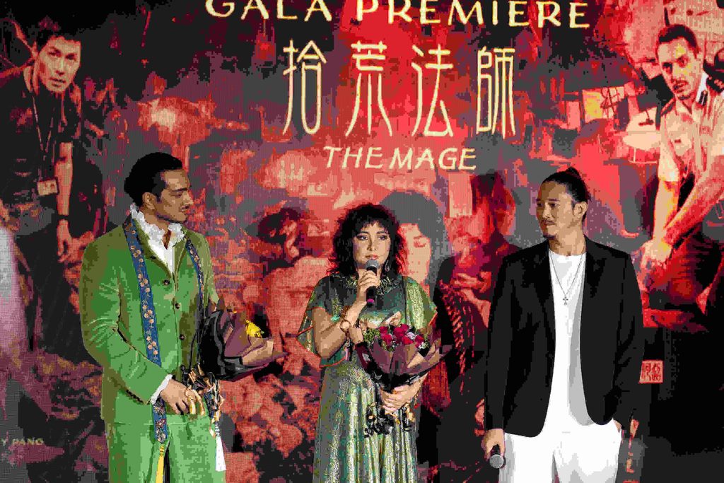 Josie Ho berucap memegang mikrofon dan jambangan bunga diapit barisan pelakon semasa tayangan perdana THE MAGE